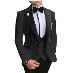 A man wears a slim-fit black three-piece suit with a bow tie and a decorative lapel pin.