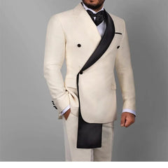 A man wears a cream-colored slim-fit suit featuring a unique black asymmetrical shawl lapel.