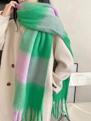 A soft, oversized plaid scarf in vibrant green and light purple worn over a beige coat.