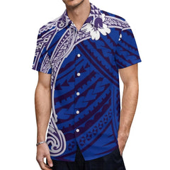 A man wears a short-sleeved button-down shirt featuring a blue and white Polynesian tribal print.