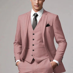 A man wears a dusty pink three-piece suit with a white shirt and a dark grey tie.