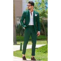 A man wears a slim-fit green two-piece suit with a white shirt and brown loafers.