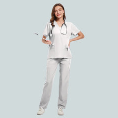 A woman wearing a white short-sleeved scrub top and matching pants with a stethoscope.