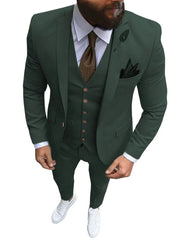 A man wears a dark green three-piece slim fit suit with a brown tie and white sneakers.