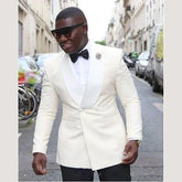A man wears a white double-breasted tuxedo jacket with a shawl lapel and a black bow tie.