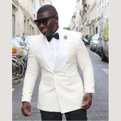 A man wears a white double-breasted tuxedo jacket with a shawl lapel and a black bow tie.
