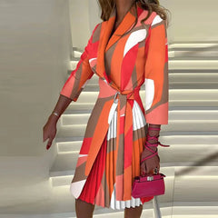 A woman wears a knee-length, V-neck dress with three-quarter sleeves and an orange geometric print.