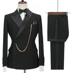 A black slim-fit two-piece suit featuring a peaked lapel blazer with a gold chain and matching pants.