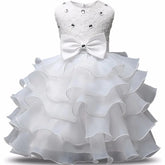 A sleeveless white knee-length dress with a lace bodice, rhinestone accents, and a large bow.