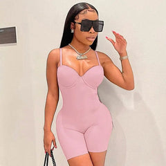 A woman wears a light pink, sleeveless, bodycon romper with a sweetheart neckline.