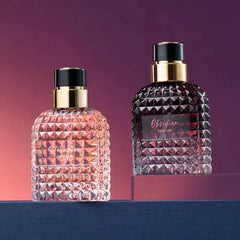 Two glass perfume bottles with textured stud patterns stand on a blue surface against a purple background.