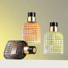 Three glass perfume bottles with textured geometric patterns stand on a white surface.