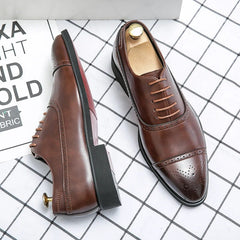 A pair of brown leather lace-up oxford brogues with decorative perforations and red soles.