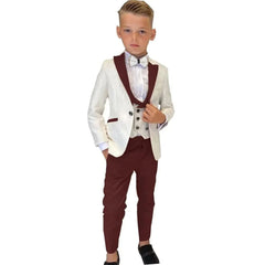 A boy wears a three-piece suit featuring a white paisley blazer with burgundy lapels, a matching vest, and burgundy trousers.