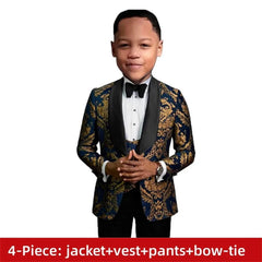 A boy wears a royal blue and gold paisley patterned tuxedo jacket with a black shawl lapel, vest, and bow tie.