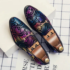 A pair of men's slip-on loafers featuring a colorful, patterned design and a gold-tone metal bit.