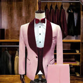 A three-piece pink slim fit suit featuring a burgundy velvet shawl lapel and matching bowtie.