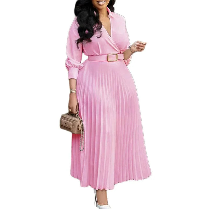 A woman wears a long-sleeved, pink pleated midi dress with a V-neck and a matching waist belt.