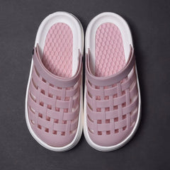 A pair of mauve platform clogs with a woven-style upper and white soles on a dark background.
