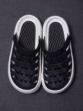A pair of black closed-toe sandals with a woven upper and a thick white platform sole.