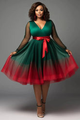 A plus size emerald green V-neck dress with sheer sleeves, a red waist tie, and a red tulle hem.