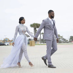 A bride wears a high-neck, long-sleeve beaded jumpsuit with a detachable tulle train.