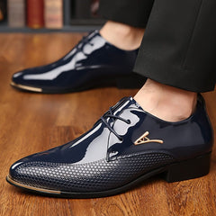A pair of navy blue faux patent leather derby shoes with a textured toe and gold metal accents.