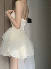 A white strapless mini dress with a fitted bodice and a layered tulle skirt.