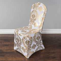 A white spandex chair cover featuring a metallic gold damask print pattern.