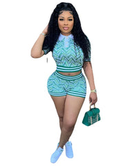 A woman wears a green and white digital print two-piece set with a collared top and shorts.