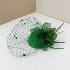 A green retro-style bridal fascinator featuring a mesh veil, fabric flower, and feather accents.