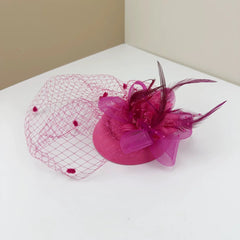 A bright pink fascinator featuring a mesh veil, decorative feathers, and a floral accent.