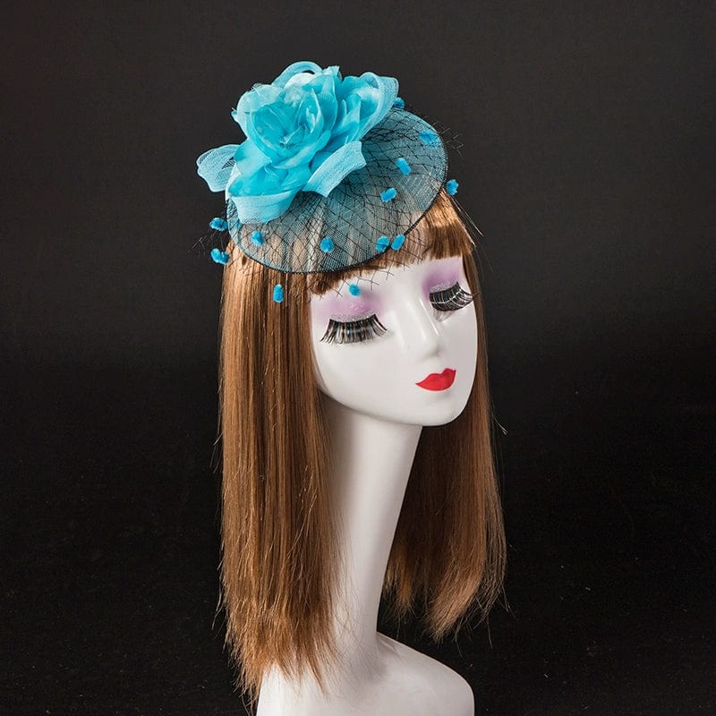 A blue fascinator hat with a large fabric flower and polka-dot netting on a mannequin head.