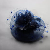 A navy blue fascinator headpiece featuring a floral accent, feathers, and a decorative veil.