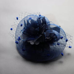 A navy blue fascinator headpiece featuring a floral accent, feathers, and a decorative veil.
