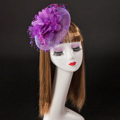 A purple fascinator hat with a large flower and feathers, displayed on a mannequin head.