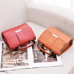 Two structured PU leather flap handbags in red and tan sit on an open magazine.
