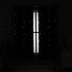 Blackout curtains with a silver star and moon pattern hanging on a window.
