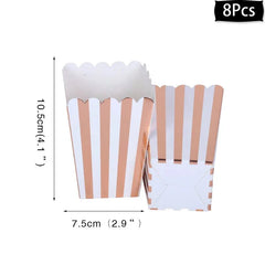 Eight rose gold and white striped paper popcorn boxes with scalloped edges.