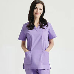 A woman wearing a light purple V-neck medical scrub top with three front pockets.