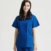 A woman wearing a royal blue V-neck short-sleeve medical scrub top with front pockets.