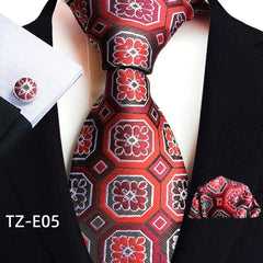 A red and black patterned necktie set with a matching pocket square and cufflinks.