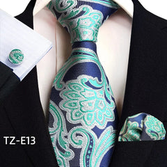 A blue and green paisley patterned necktie set with a matching pocket square and cufflinks.