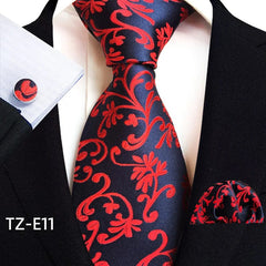 A navy blue necktie, pocket square, and cufflink set featuring a vibrant red paisley pattern.