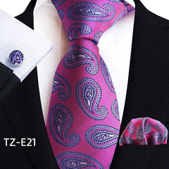 A magenta necktie with a blue paisley pattern, matching pocket square, and cufflinks.