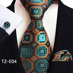 A black, orange, and blue geometric patterned necktie with a matching pocket square and cufflink.