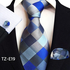 A blue and grey checkered necktie, pocket square, and matching cufflink set on a black suit.