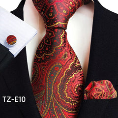 A red and black paisley patterned necktie set with a matching pocket square and cufflinks.