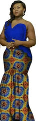A woman wears a blue one-shoulder top paired with a matching patterned floor-length skirt.