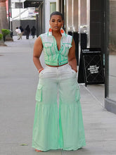 A woman wears a mint green two-piece set featuring a sleeveless button-up vest and flared pants.